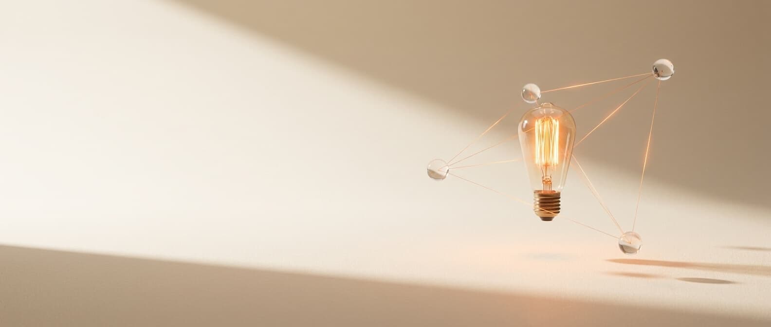 Glühbirne mit feinen orange Verbindungslinien zu schwebenden Glas-Kugeln — Netzwerk-Topologie als ruhige Struktur